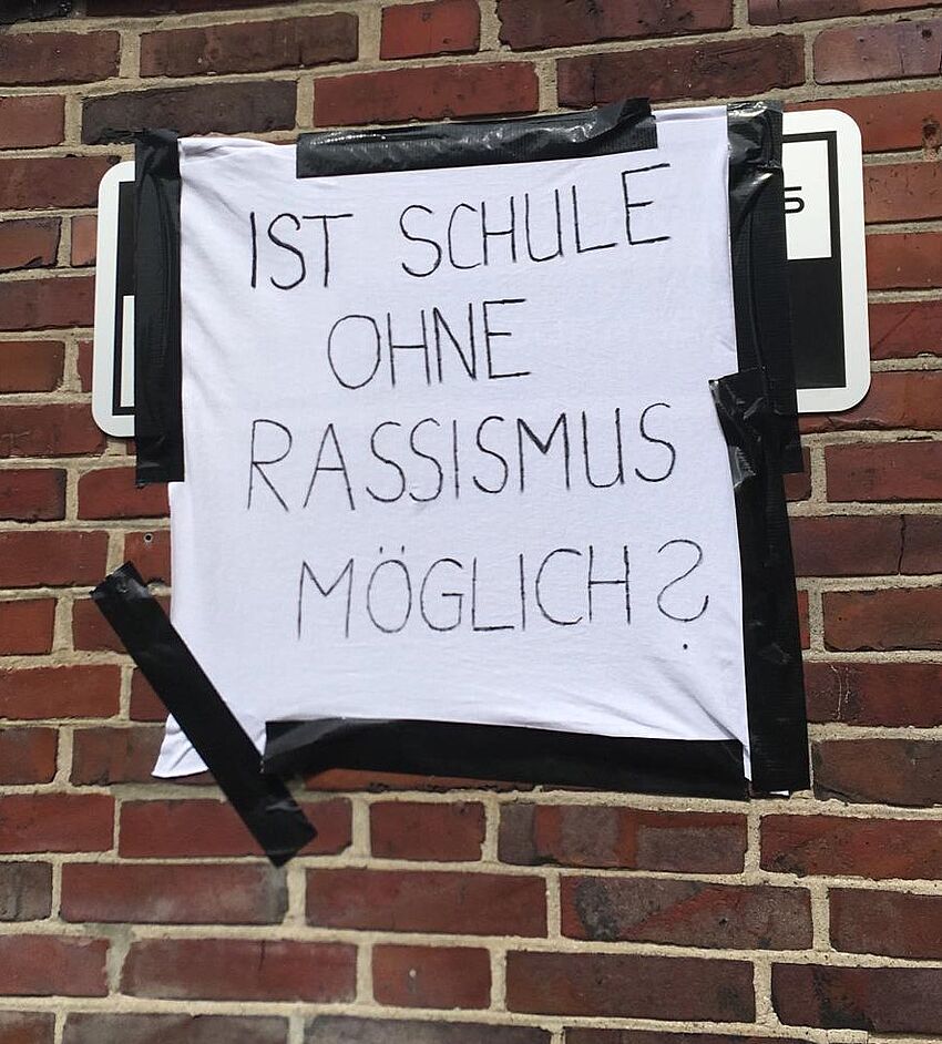 Foto: Plakat an Hauswand mit Aufschrift: Ist Schule ohne Rassismus möglich?